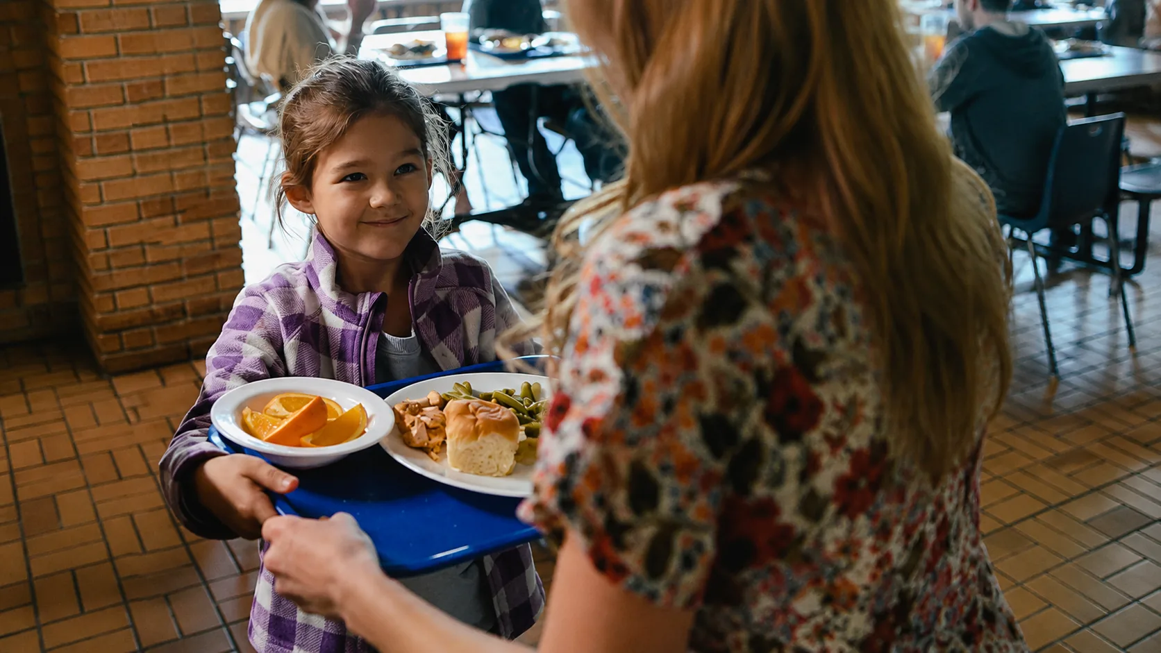 A young girl smiling while receiving a hot meal from The Salvation Army